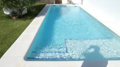 a swimming pool with blue water in a yard at Villa Lolo de design con Piscina, Jardin y Parking exclusivo in Chiclana de la Frontera