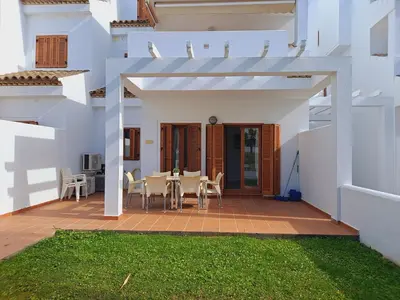 a white house with a patio with a table and chairs at Apartamentos Turísticos La Carrajolilla in Chiclana de la Frontera