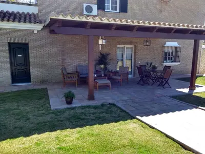a patio with a table and chairs under a pergola at Dunas villa in El Puerto de Santa María