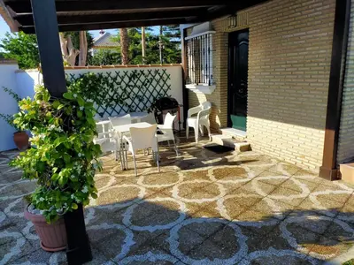 a patio with white chairs and a brick wall at Dunas villa in El Puerto de Santa María