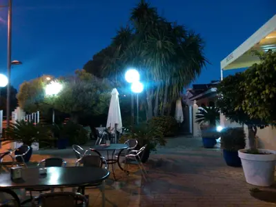 an outdoor patio with tables and chairs at night at Hotel Las Canteras de Puerto Real in Puerto Real