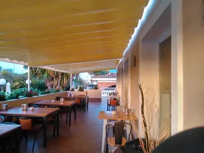 a restaurant with wooden tables and chairs and a patio at Hotel Las Canteras de Puerto Real in Puerto Real