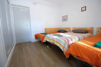 two twin beds in a room with wooden floors at Oasis en la playa in Chiclana de la Frontera