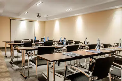 a conference room with tables and chairs and a screen at Eurostars Asta Regia Jerez in Jerez de la Frontera