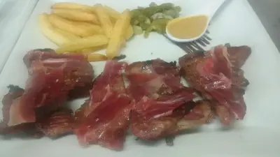 a plate of food with meat and french fries at Hotel Restaurante Calderon in Arcos de la Frontera