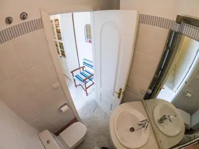 a bathroom with a toilet and a sink and a chair at La Terraza del Drago in Cádiz