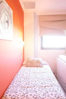 a bed in a bedroom with an orange wall at Apartamento Racimo El Puerto de Santa Maria in El Puerto de Santa María