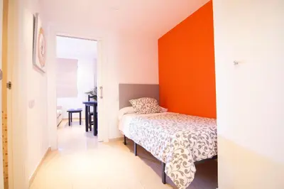 a bedroom with a bed and an orange wall at Apartamento Racimo El Puerto de Santa Maria in El Puerto de Santa María