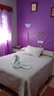 a purple bedroom with a bed with two towels on it at Hostal Andalucia de Arcos in Arcos de la Frontera