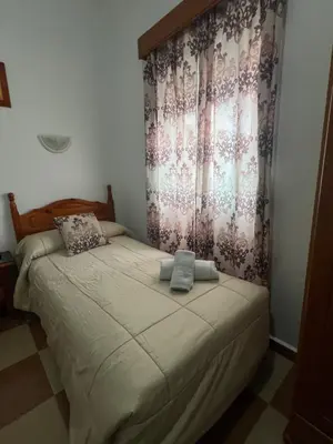a small bedroom with a bed with a curtain at Hostal Andalucia de Arcos in Arcos de la Frontera
