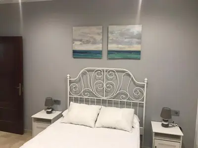 a bedroom with a white bed with three paintings on the wall at Rincón en el Mentidero in Cádiz