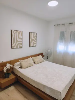 a bed in a bedroom with two pictures on the wall at COSTA EL CASTILLO Apartamento con WIFI in Chiclana de la Frontera