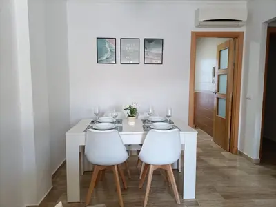 a white dining room with a white table and two white chairs at COSTA EL CASTILLO Apartamento con WIFI in Chiclana de la Frontera