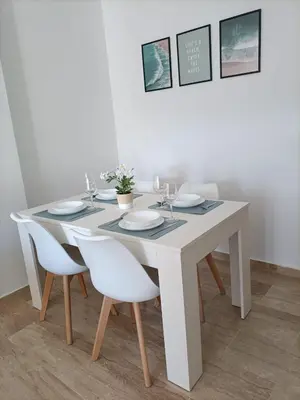 a white dining room table with white plates and chairs at COSTA EL CASTILLO Apartamento con WIFI in Chiclana de la Frontera