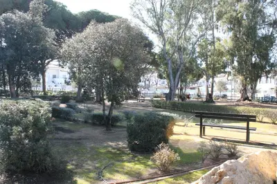 a park with a bench and trees and bushes at COSTA EL CASTILLO Apartamento con WIFI in Chiclana de la Frontera
