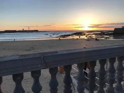 a view of the beach at sunset from a balcony at Levante by Gades Gestión in Cádiz