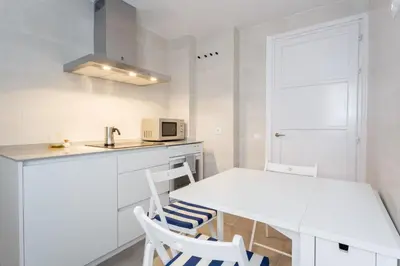 a white kitchen with a table and two chairs at FARO Family Home by Cadiz4Rentals in Cádiz
