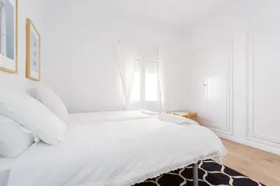 a white bedroom with a white bed and a window at FARO Family Home by Cadiz4Rentals in Cádiz