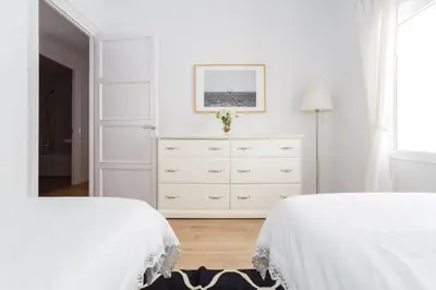 a white bedroom with two beds and a dresser at FARO Family Home by Cadiz4Rentals in Cádiz