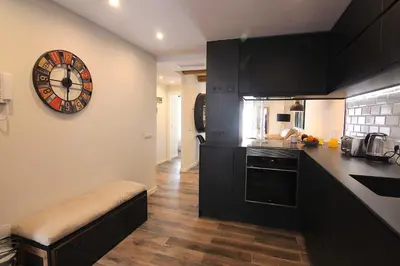 a kitchen with black cabinets and a clock on the wall at El CONSEJERO de Indias free parking by Cadiz4Rentals in Cádiz