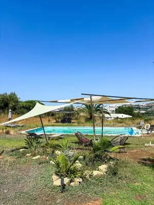a pool with a tan umbrella and some chairs at bungalow entre mer et montagne in Arcos de la Frontera