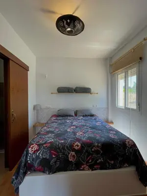 a bedroom with a bed with a floral comforter at bungalow entre mer et montagne in Arcos de la Frontera