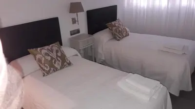 a small room with two beds with white sheets at GUESTING VELAZQUEZ in Cádiz