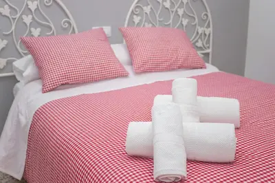 a bed with red and white sheets and pillows at Multi Apartamentos La Kasbah in Jerez de la Frontera