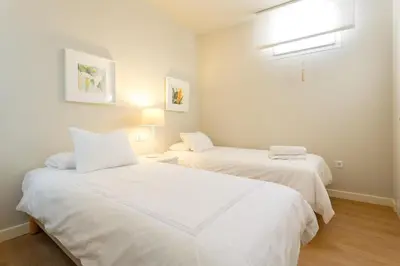 two beds in a room with white sheets at Diseño y confort junto a la catedral in Cádiz