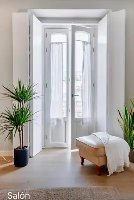 a white room with a door and a bench and plants at Diseño y confort junto a la catedral in Cádiz