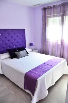 a bedroom with a large bed with a purple headboard at Apartamentos Turísticos La Boutique del Mar in Conil de la Frontera