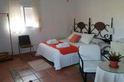 a bedroom with a bed and a couch and a chair at Bungalow Cuesta de la Rosa. Casita rural con encanto y vistas in Arcos de la Frontera