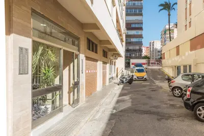 a street with cars parked in front of a building at Villamar in Cádiz