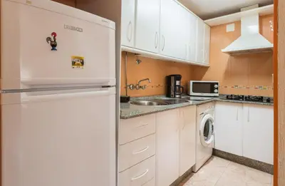 a kitchen with white cabinets and a refrigerator at Villamar in Cádiz