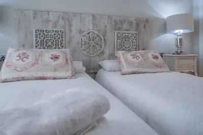 a bedroom with two beds with white sheets and pink pillows at Apartamento Sueño de la Caleta in Cádiz