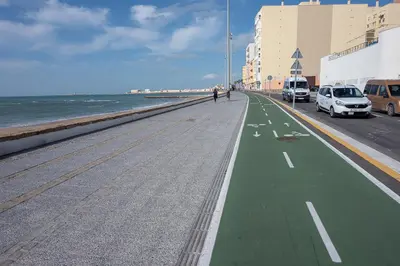 a street with a green sidewalk next to the ocean at Gran Apartamento Avenida 57 in Cádiz