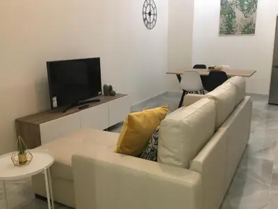 a living room with a white couch and a tv at Apartamento nuevo en casa tipo palacio in Cádiz