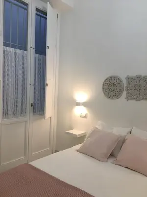 a white bedroom with a bed and a window at Apartamento nuevo en casa tipo palacio in Cádiz