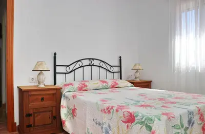 a bedroom with a bed and two night stands with lamps at Chalet Aroca in Conil de la Frontera