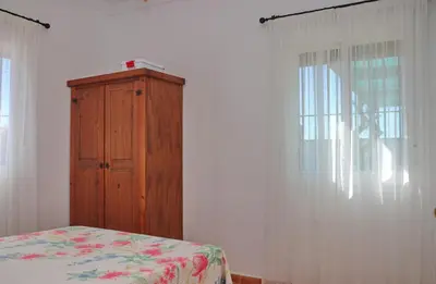 a bedroom with a wooden cabinet next to a bed at Chalet Aroca in Conil de la Frontera