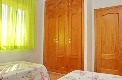 a bedroom with two wooden cabinets and a bed at Chalet Aroca in Conil de la Frontera