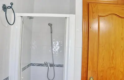a shower in a bathroom next to a wooden door at Chalet Aroca in Conil de la Frontera