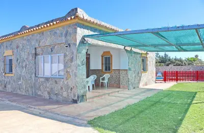 a stone house with a patio and a red fence at Chalet Aroca in Conil de la Frontera