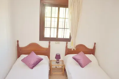 two beds in a room with two purple pillows at San Nicolás in Algar