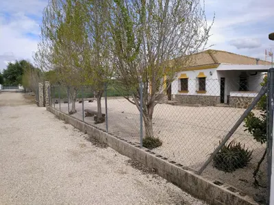 a fence in front of a house with a tree at San Nicolás in Algar