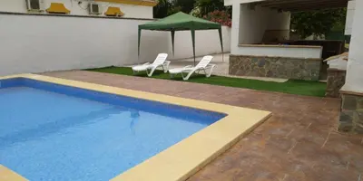 a swimming pool with two chairs and a green umbrella at San Nicolás in Algar