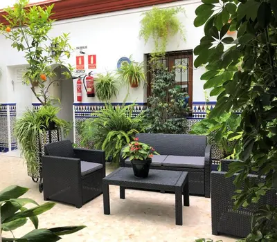 a patio with chairs and a table and plants at Hostal Mellizo in Lebrija