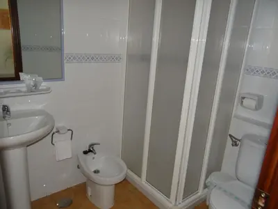 a bathroom with a shower and a toilet and a sink at Hostal Mellizo in Lebrija