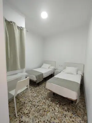 a room with two beds and a chair in it at Hostal Mellizo in Lebrija