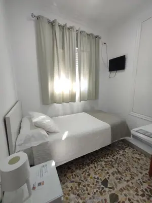 a small bedroom with a bed and a window at Hostal Mellizo in Lebrija